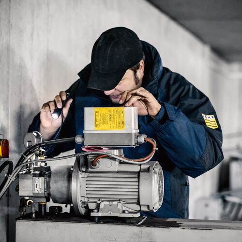 Mann mit Taschenlampe überprüft Motor