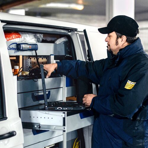 Mann räumt Werkzeuge in sein Auto