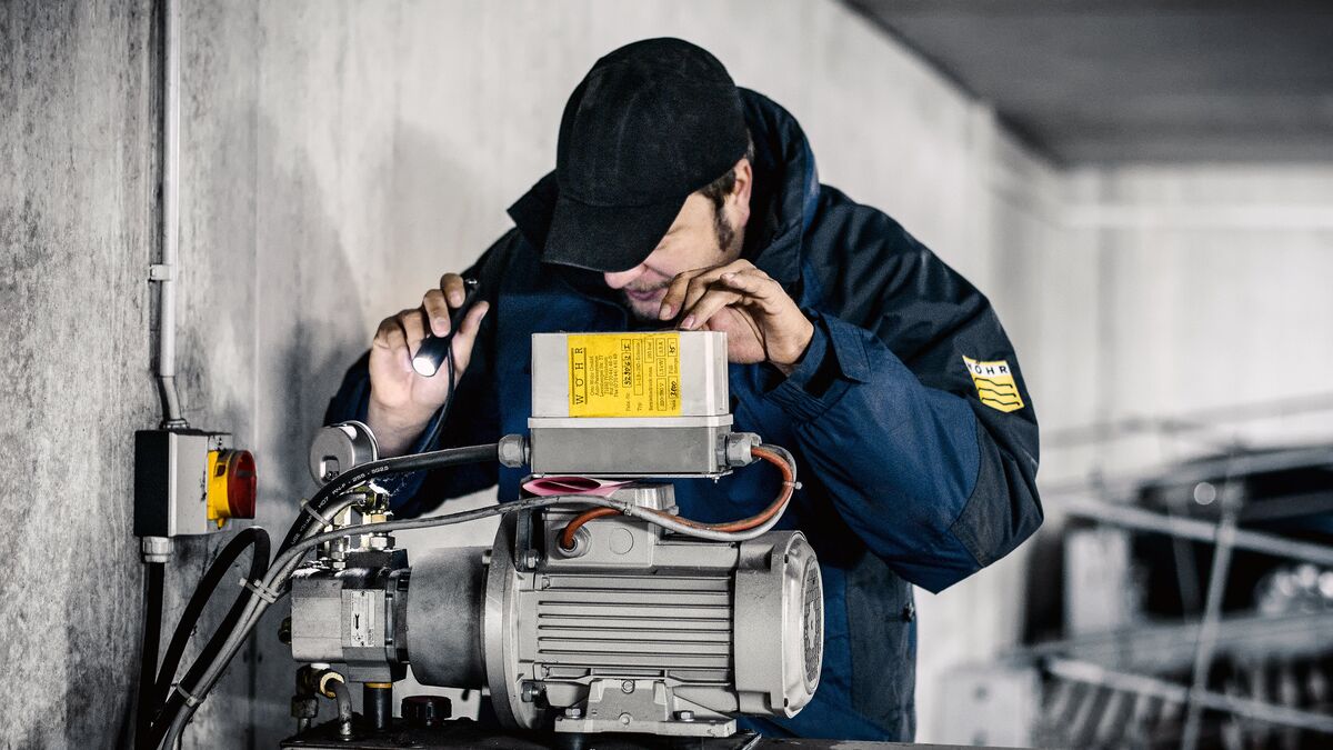 Mann mit Taschenlampe überprüft Motor